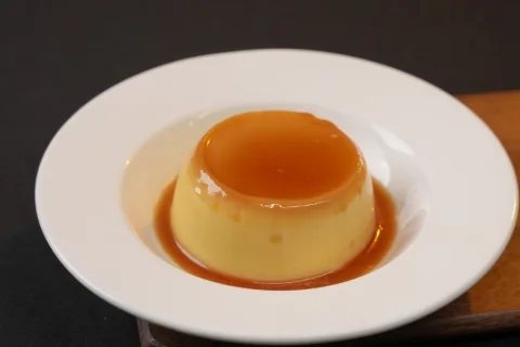 A caramel custard dessert on a white plate, shot for a restaurant menu